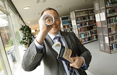 Dr. Mittermaier schaut im Lesesaal der Zentralbibliothek durch eine zusammengerollte Publikation.